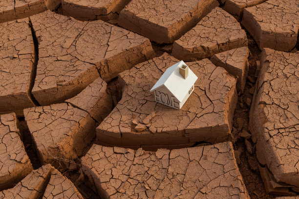 一座有象征意义的木屋矗立在沙漠中开裂的红粘土上图片下载