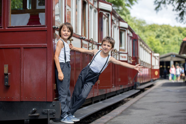 漂亮的孩子们，穿着复古的衣服，在炎热的夏天享受着老式的蒸汽火车图片下载