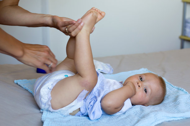 妈妈在托儿所给她快乐的宝宝穿上尿布图片下载