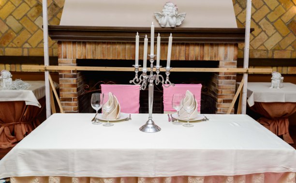 两个人的餐桌布置，白色的盘子，米色的餐巾，烛台和桌布上的餐具。优雅的餐桌布置。为婚宴准备的桌子图片下载