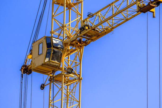 黄色建筑起重机与机舱特写蓝天背景。概念起重货物，工程机械和现代技术照片图片下载