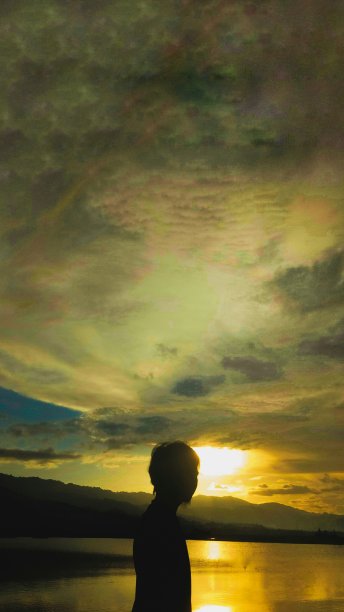 站在岩石上，直视前方。自然与美的概念。橙色的日落。日落时剪影。图片下载