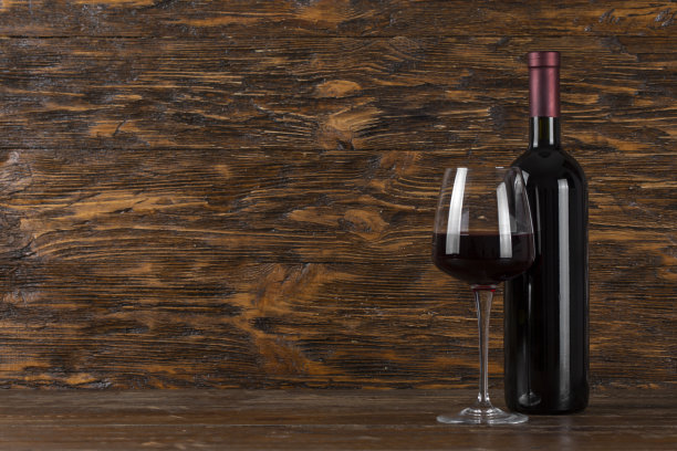 木制背景上的酒瓶和玻璃杯。空间的文本。图片下载