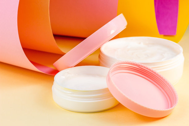 白色塑料化妆品容器的保湿霜作为一个明亮的粉红色，橙色和黄色的背景模拟。身体和皮肤护理，健康，健康和美容的概念图片下载