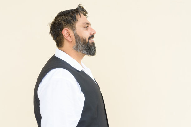 相貌英俊、大胡子的印度男子的侧面画像，背景朴素图片下载