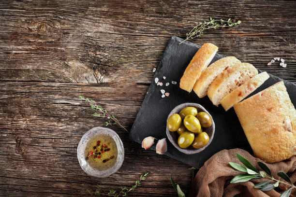 桌上放着初榨橄榄油、橄榄和新鲜面包。俯视图图片下载