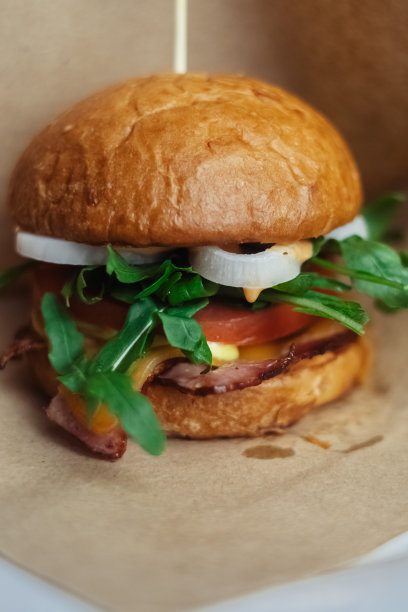 一个标准汉堡的特写镜头。餐馆或咖啡馆里的成人快餐。微距照片的汉堡原料与肉，奶酪和香草。为全家准备的环保汉堡图片下载