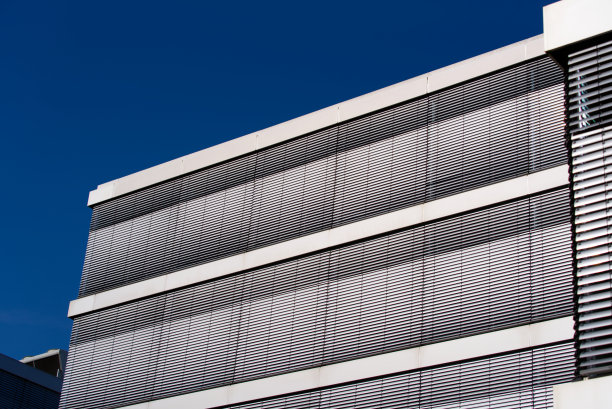 在明亮的阳光下关闭百叶窗的办公楼立面特写。图片下载