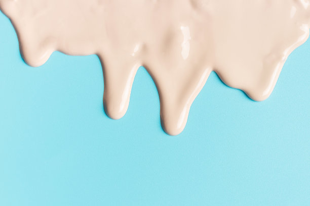 米色粉底滴在蓝色背景特写。图片下载