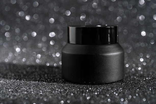 闪亮的派对背景上的黑色化妆瓶。图片下载