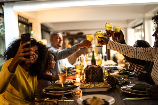 年轻女子正在视频通话/拍摄/拍摄一家人在家里庆祝圣诞晚餐的照片图片下载