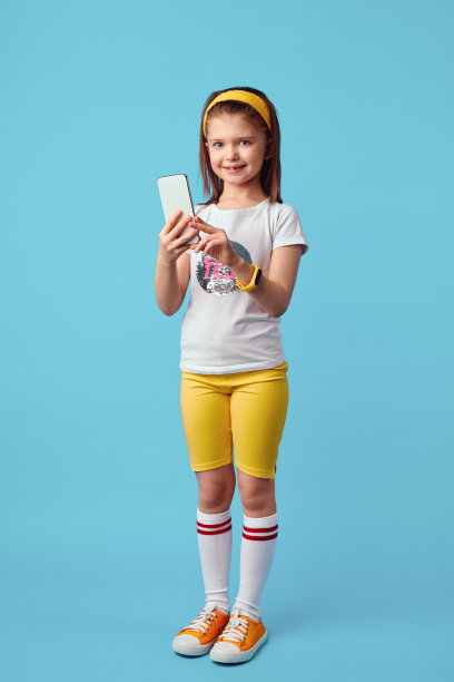 可爱的女孩身穿白色t恤，手拿手机，站在蓝色图片下载