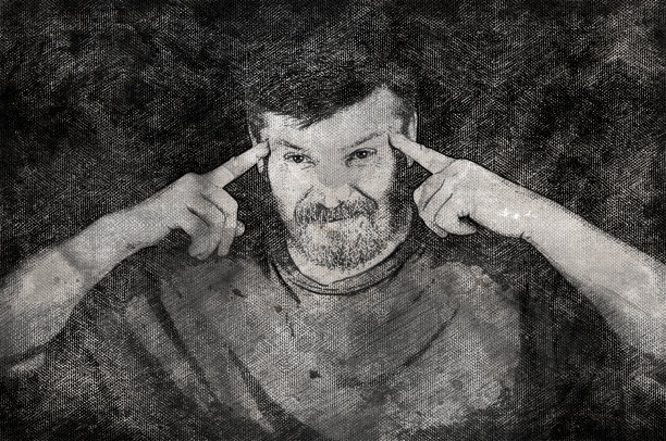 一个男人的黑白画像，他把食指放在太阳穴上。黑色背景下的中年人。图片下载