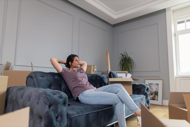 放松的女人在她的新客厅的沙发上做着白日梦。图片下载