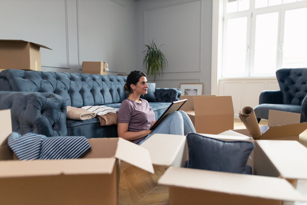 微笑的女人在新公寓打开她的回忆后做着白日梦。图片下载