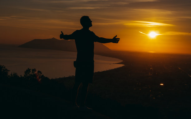 的旅程。一个男人站在山顶上看日落。图片下载