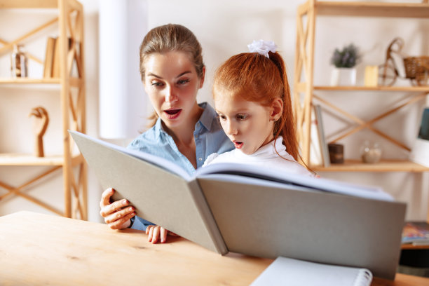 母亲和女儿一起读书的照片，家人的表情搞笑而兴奋图片下载