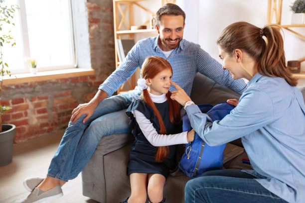 幸福微笑的家庭，父亲和母亲，为小女孩准备上学的全身图像。包装的背包图片下载