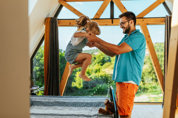 爸爸和活泼的小女孩在床上蹦蹦跳跳图片下载