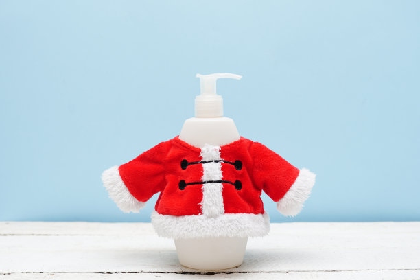 圣诞化妆瓶洗发水或沐浴露在圣诞老人服装在蓝色背景图片下载