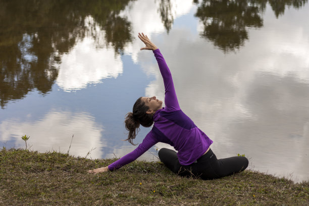 女人锻炼瑜伽在一个池塘前面与云在水中的倒影。图片下载