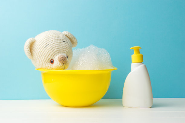 一只正在洗澡的针织熊和一瓶洗涤剂。图片下载