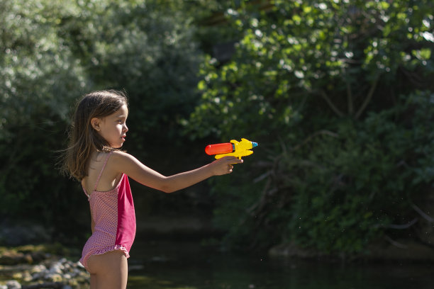 女孩在河里玩着水枪图片下载
