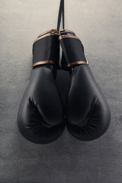 在黑暗的环境中，一副拳击手套挂在混凝土墙上图片下载