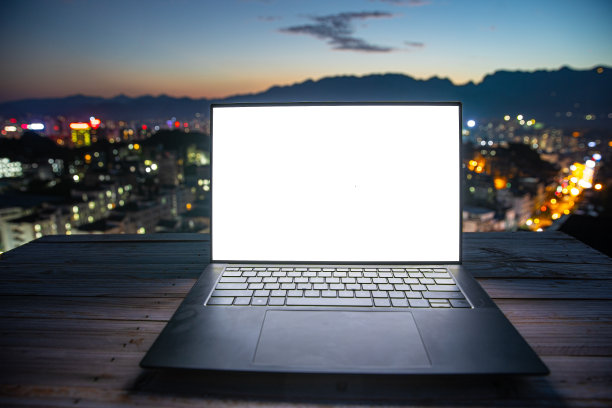 白屏笔记本电脑与城市的夜晚背景图片下载