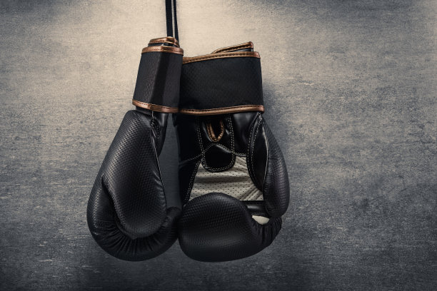 在黑暗的环境中，一副拳击手套挂在混凝土墙上图片下载