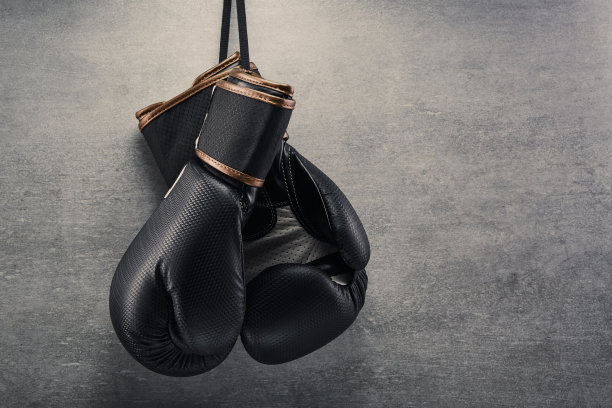 在黑暗的环境中，一副拳击手套挂在混凝土墙上图片下载