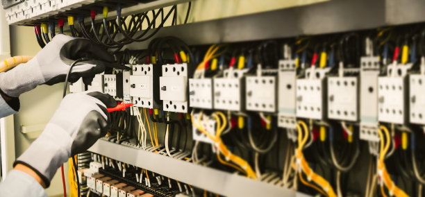 电气工程师用万用表测量保护继电器上的电气装置和线路。图片下载