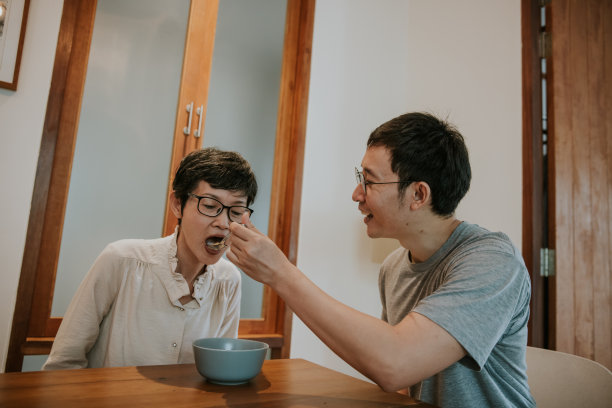 亚洲快乐的儿子在早餐时间喂他的母亲麦片照片图片下载