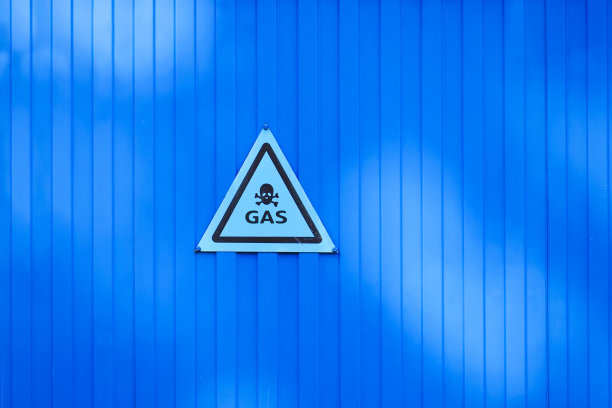 蓝色围墙上的气体设备警告。注意气体、警告标志、压力气体管道图片下载