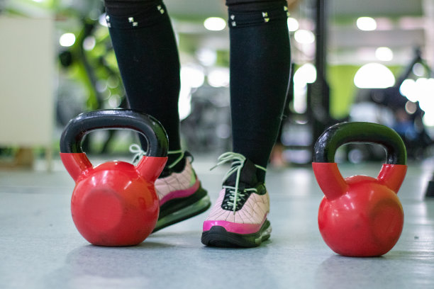 交叉训练器材:一个不知名的女人的脚穿着运动服站在一个牛铃旁边。库存图片图片下载