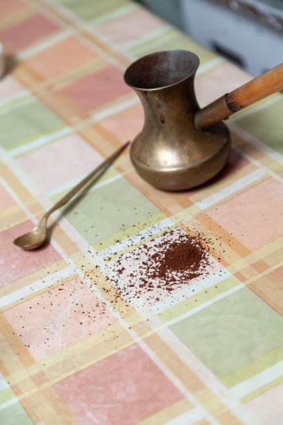 黄铜咖啡壶在桌子上。咖啡粉散落在附近图片下载
