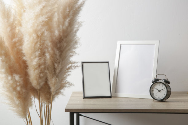 木制框架模型桌上与黑色闹钟。室内装饰元素采用中性色调。白墙的背景。图片下载