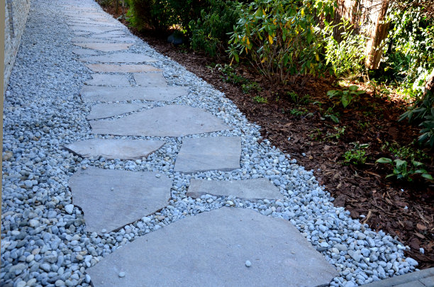 铺有大而平的斑岩。在铺路处铺上一些砾石，然后在接缝处填满砾石。由褐色不规则石板砌成的花园自然小径图片下载