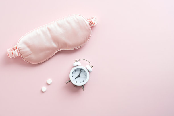 睡眼罩，闹钟，粉色背景的药片。失眠治疗的概念。图片下载