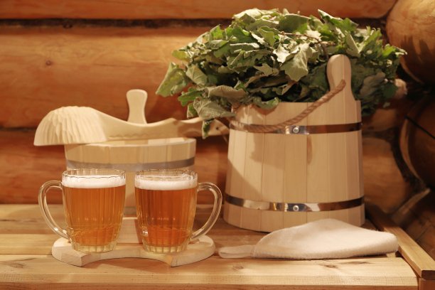 两杯啤酒在桑拿浴室配件的背景上。图片下载