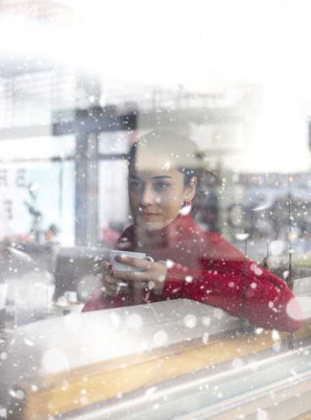 一个女人在外面的雪里喝咖啡。图片下载