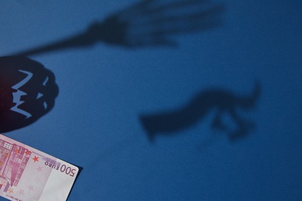 女巫的影子，手骷髅，蓝色背景上有欧元钞票的万圣节南瓜。简约的场景。图片下载