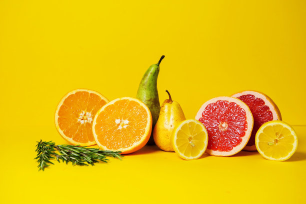 热带水果柚子，橘子，酸橙和梨在黄色背景与迷迭香小枝。理想的广告健康食品，一个关于维生素和健康生活方式的博客。本空间图片下载