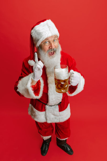穿着圣诞老人服装的老人肖像，手拿着大杯泡沫啤酒杯。啤酒节图片下载