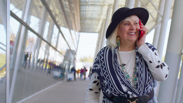 老奶奶老奶奶走在国际机场大厅里，用手机聊天图片下载