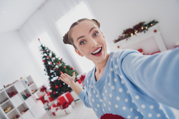 照片欢快迷人的年轻惊奇的女人展示手树圣诞节的心情在屋里图片下载