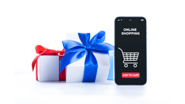 在线的礼物。网上商店应用在数字智能手机屏幕与礼品盒红丝带在网上购物构成。圣诞节销售和折扣促销。图片下载