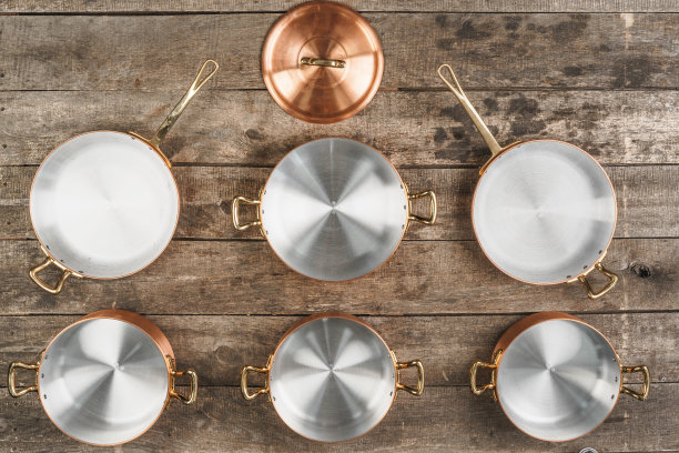 在陈旧的木制背景上布置铜烹饪锅图片下载