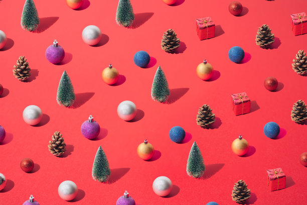 绿色新年和圣诞树与银，黄金，蓝色，红色，紫色的小玩意，礼物和棕色锥形在红色的背景。模式。图片下载