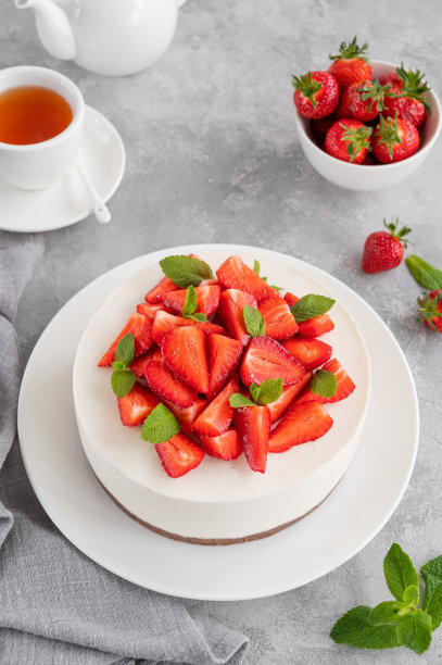 没有烤芝士蛋糕，上面有新鲜的草莓和薄荷，白色的盘子，灰色的混凝土背景。副本的空间。图片下载